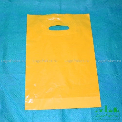 Активированный пакет желтого цвета с прорубной ручкой лежит на синем фоне. Вид спереди.